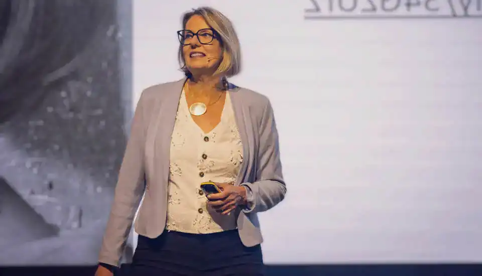 Dorothee Töreki: Professionelle Keynote-Speakerin Dorothee Töreki lächelnd auf Bühne mit Klicker bei Vortrag Keynote.