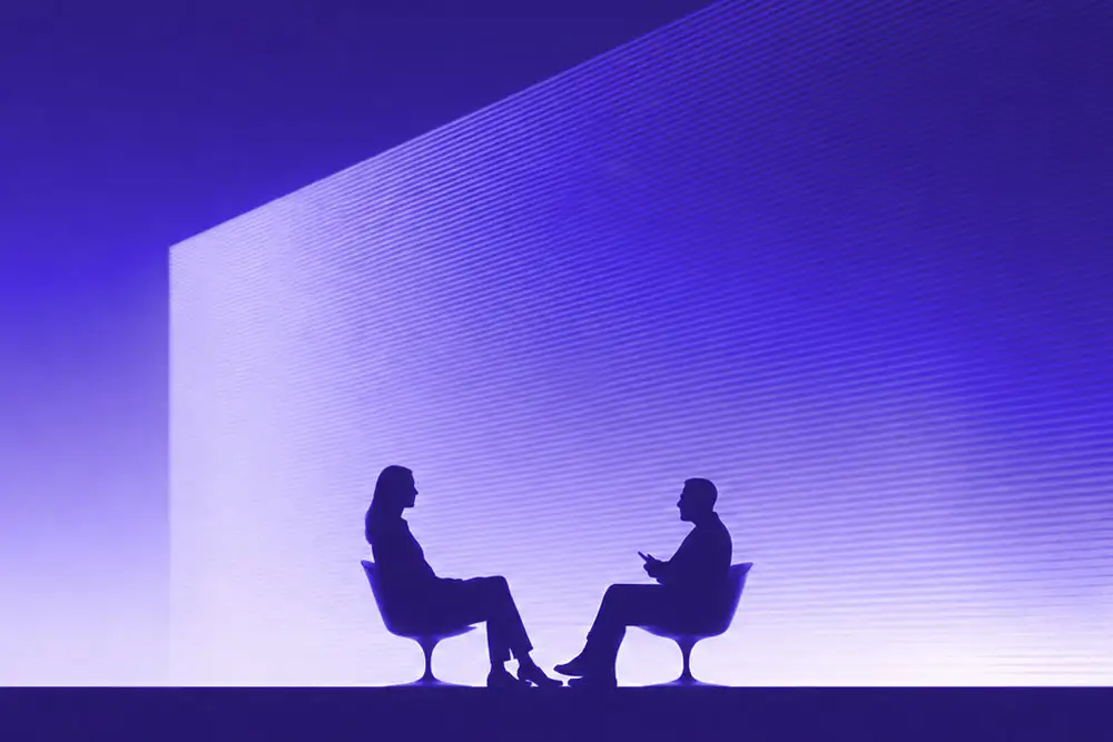Silhouetten von zwei Personen im Gespräch vor violetter Lichtwand.
